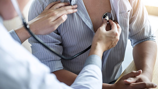 A doctor uses a stethoscope to listen to a man's heartbeat.